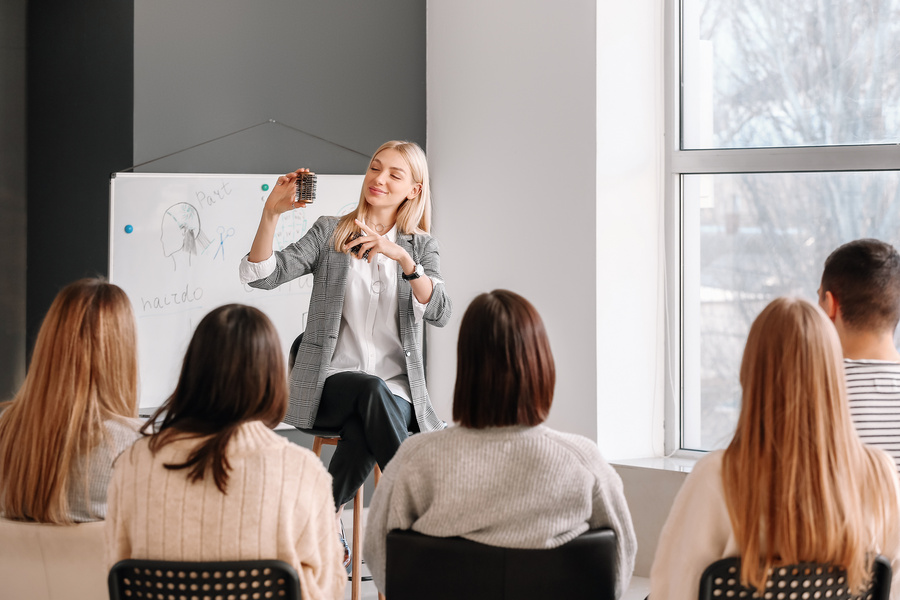 Professional Hairdresser Teaching Young People in Office